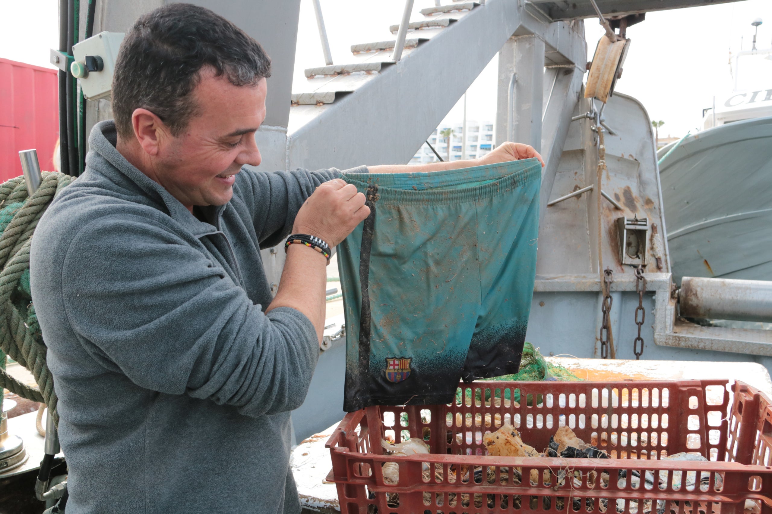 Un pescador de l'Ametlla de Mar mostra uns pantalons del Barça, una de les deixalles que han retirat de la mar en el marc del projecte Pesca Neta | Ariadna Escoda (ACN)