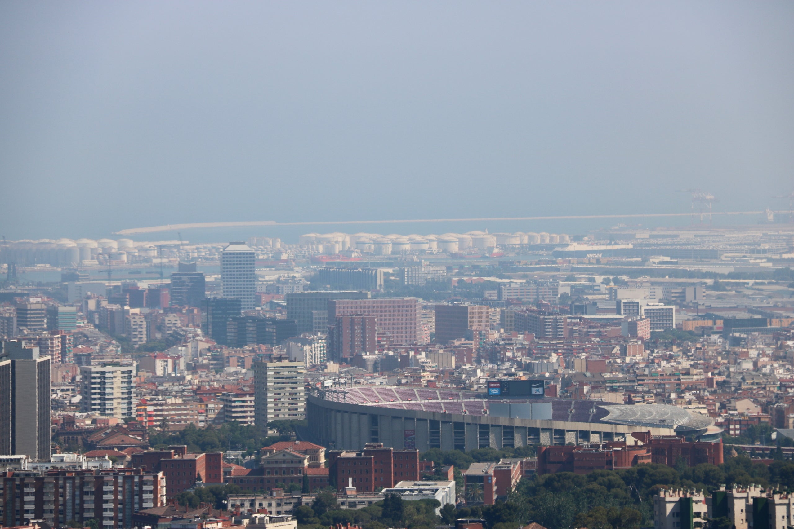 Pla general de Barcelona amb el Camp Nou en primer pla i el port de fons amb boira per pol·lució al fons després que s'hagi declarat l'episodi per alta contaminació per partícules a Catalunya, l'1 de juliol del 2019. (Horitzontal) | Nazaret Romero