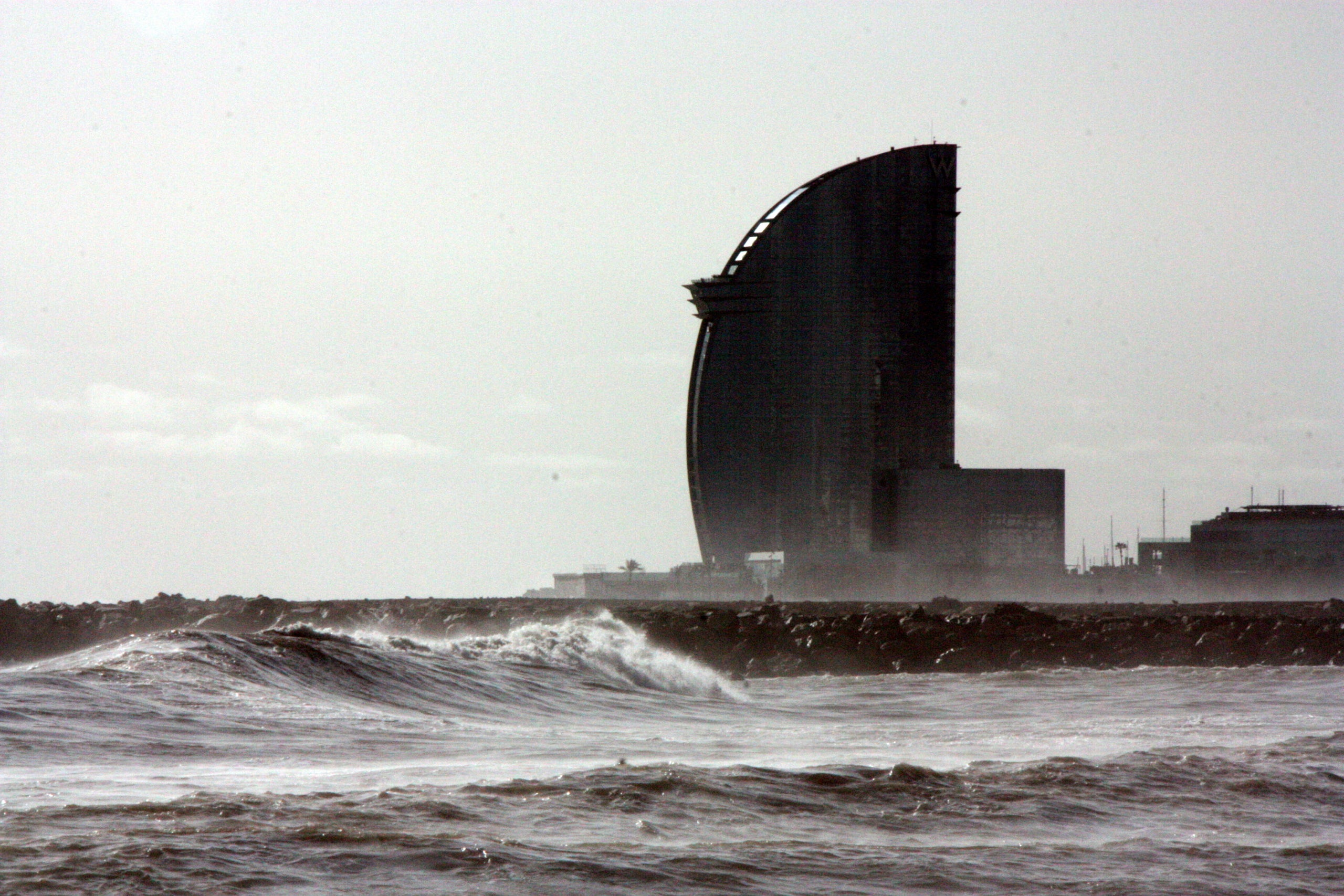 Primer plano de las olas en la playa de la Barceloneta con el Hotel Vela al fondo / ACN