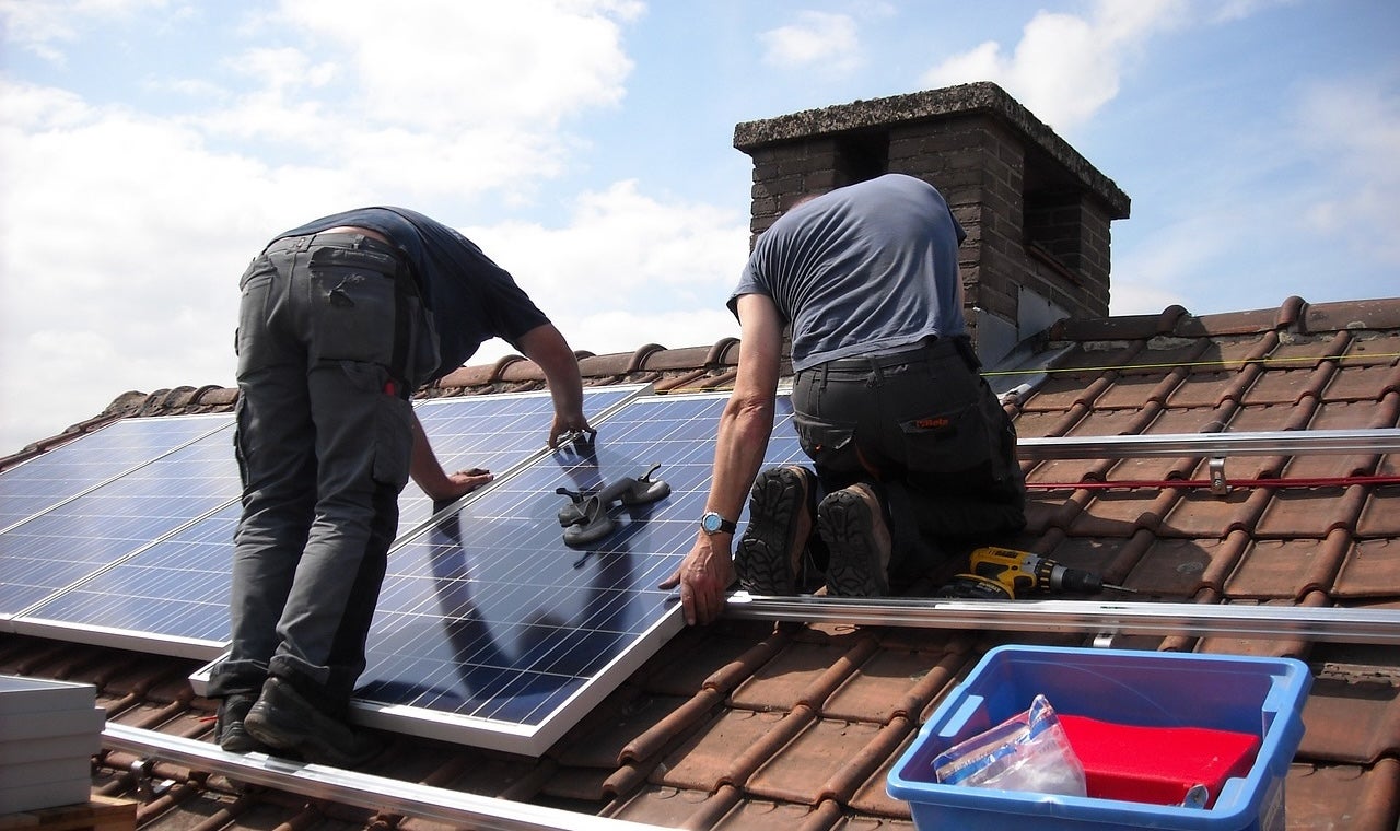 Dos operaris instal·lant plaques fotovoltaiques per al consum d'energia solar en una casa particular / Pixabay