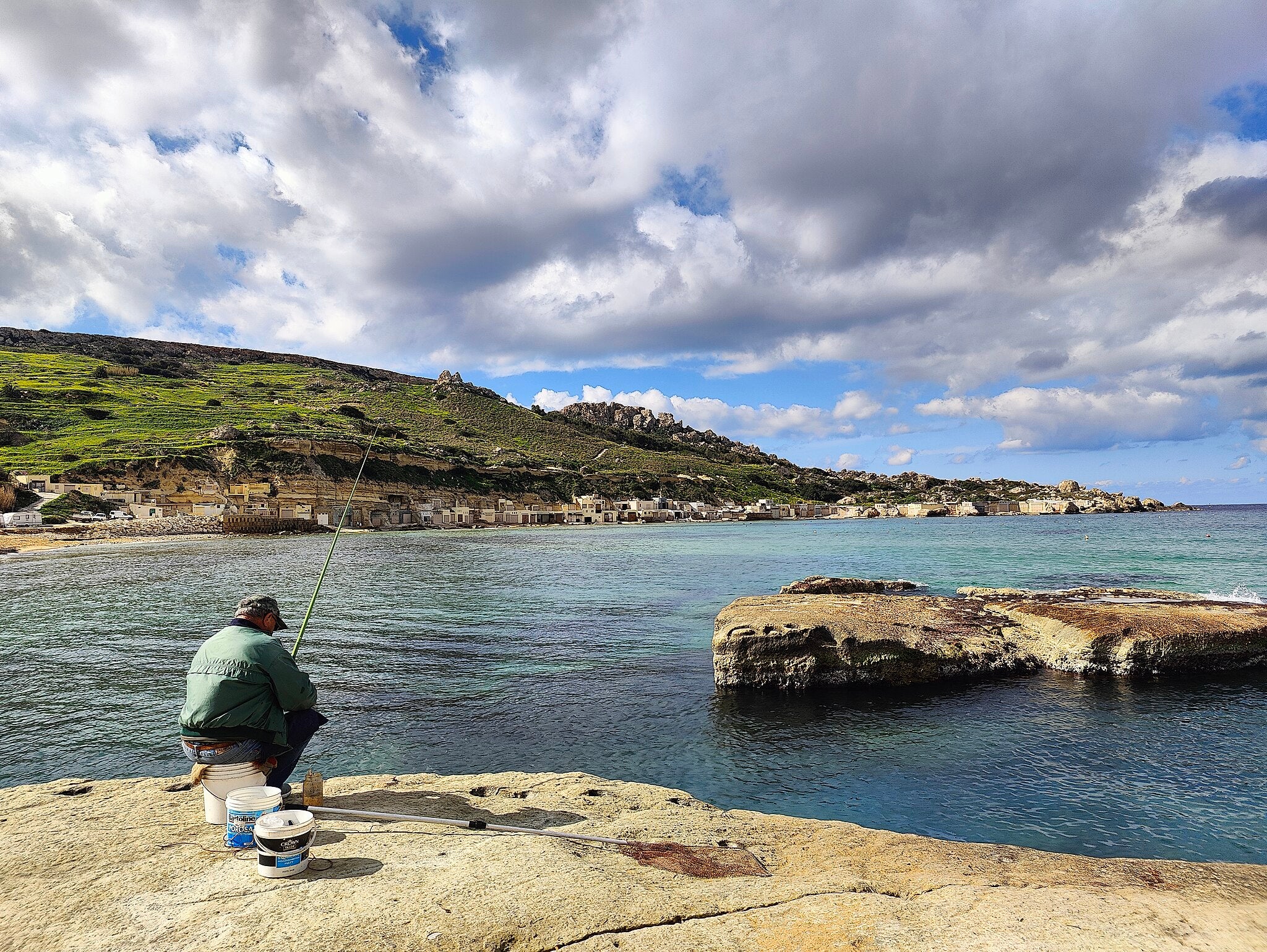 Un hombre pescando en la bahía de Ġnejna, en Malta | Wikimedia Commons