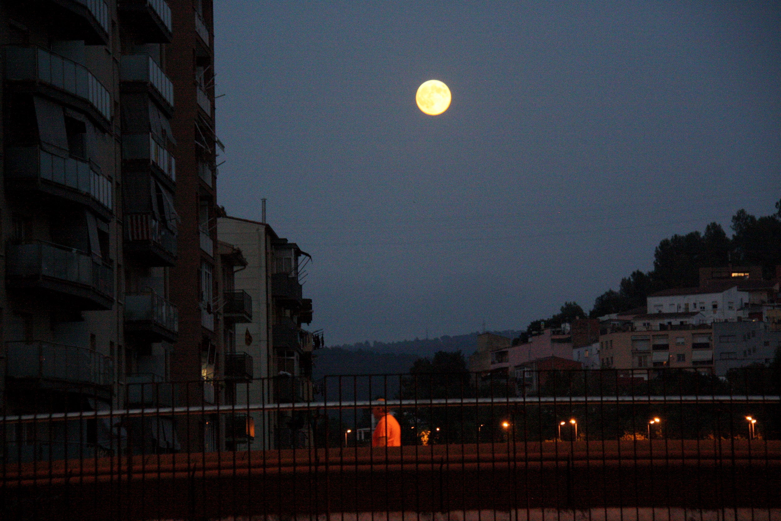 La lluna plena sortint enmig d'uns edificis a Girona / ACN