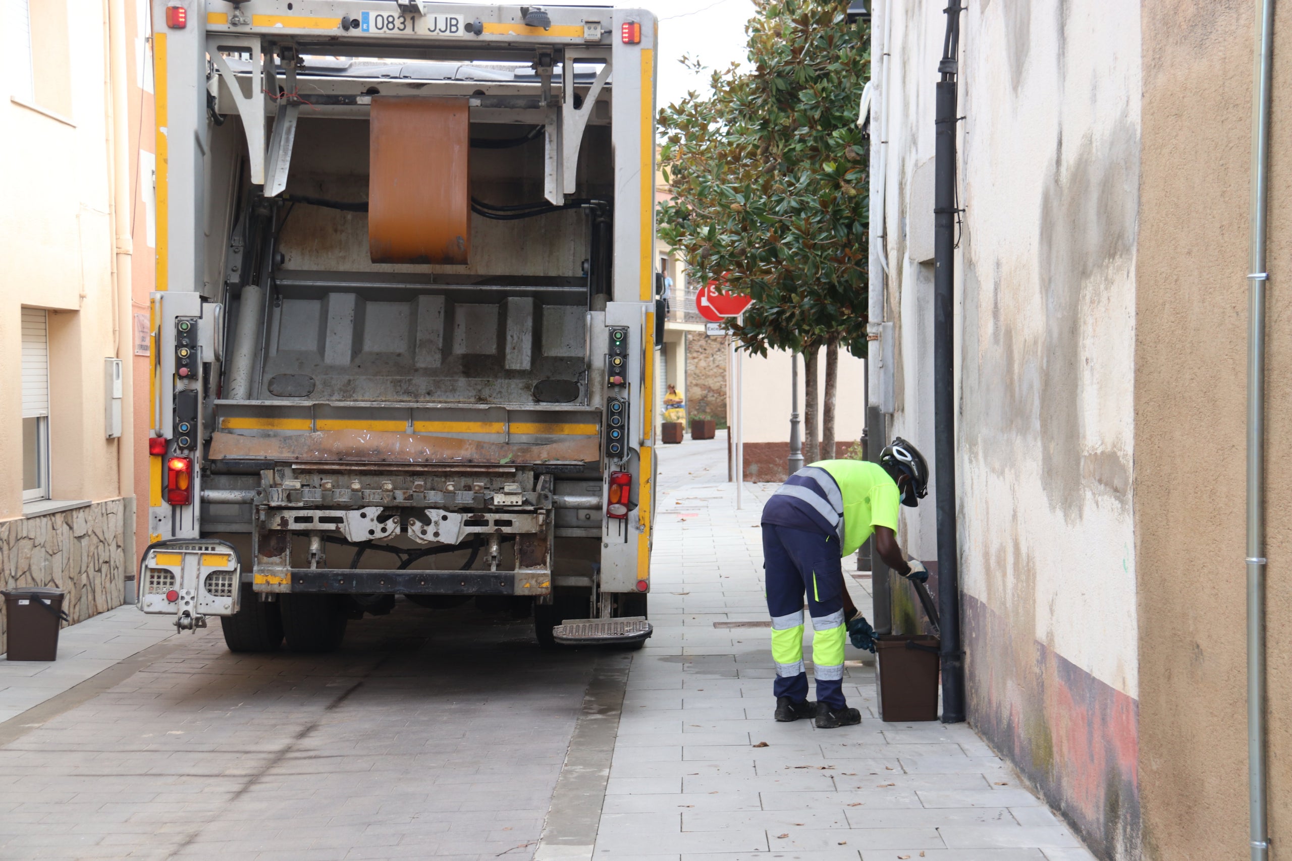 Plano general de un camión de la basura con un trabajador vaciando el cubo de la fracción orgánica durante la recogida puerta a puerta de Riudellots de la Selva el 23 de noviembre de 2020 (Horizontal) | Aleix Freixas (ACN)