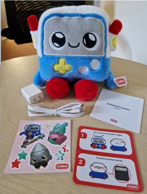 Fotografía de Gabbo, el juguete con inteligencia artificial utilizado en el estudio, junto con accesorios como el cable de carga, pegatinas, instrucciones e información de seguridad. | Universitat de Cambridge