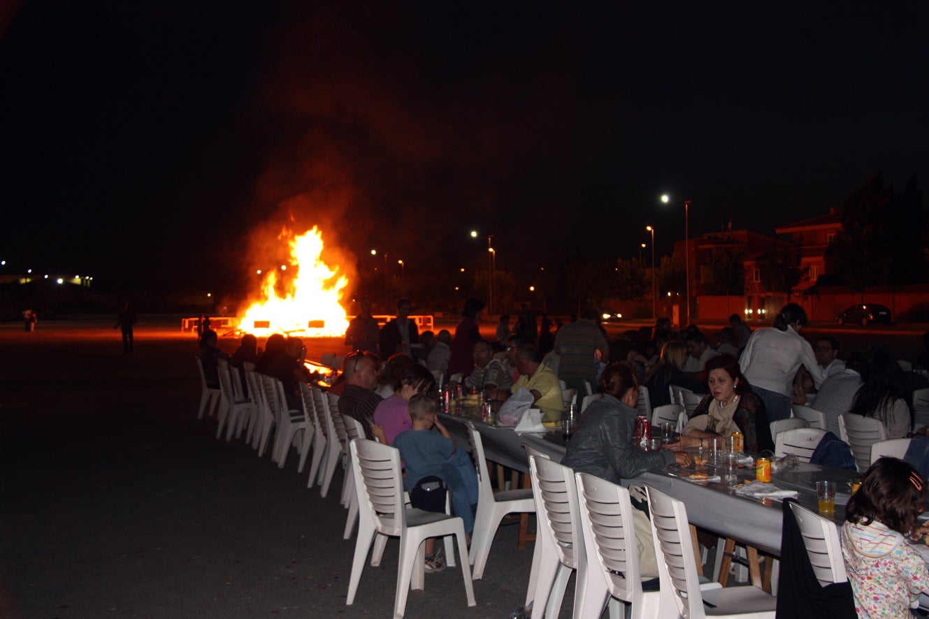 Les taules del sopar popular de la revetlla de Mollerussa, amb el foc de Sant Joan al fons. | Bosch, Oriol (ACN)