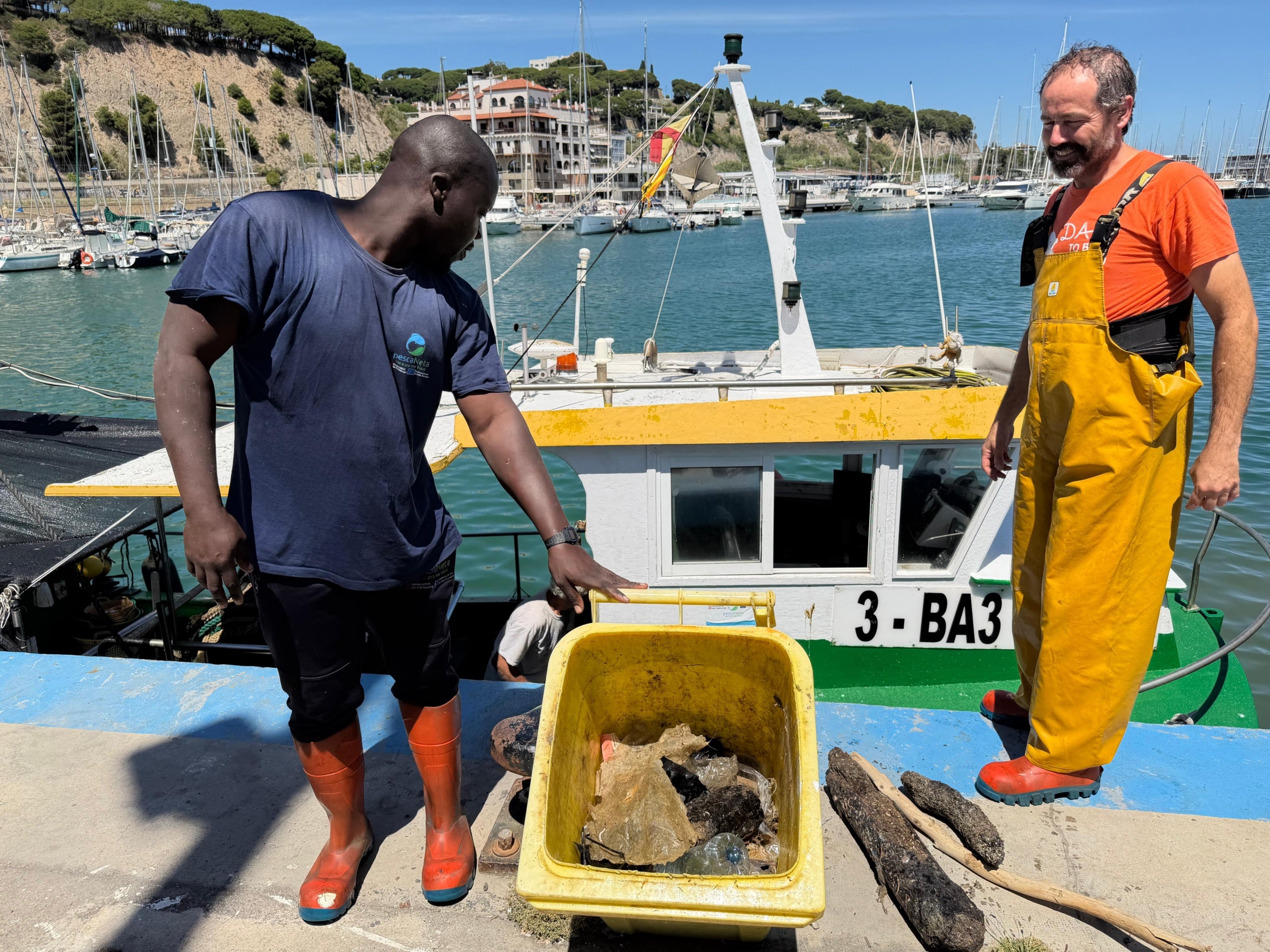 Dos pescadors d'Arenys de Mar mostrant la brossa recollida al mar | Àlex Recolons (ACN)