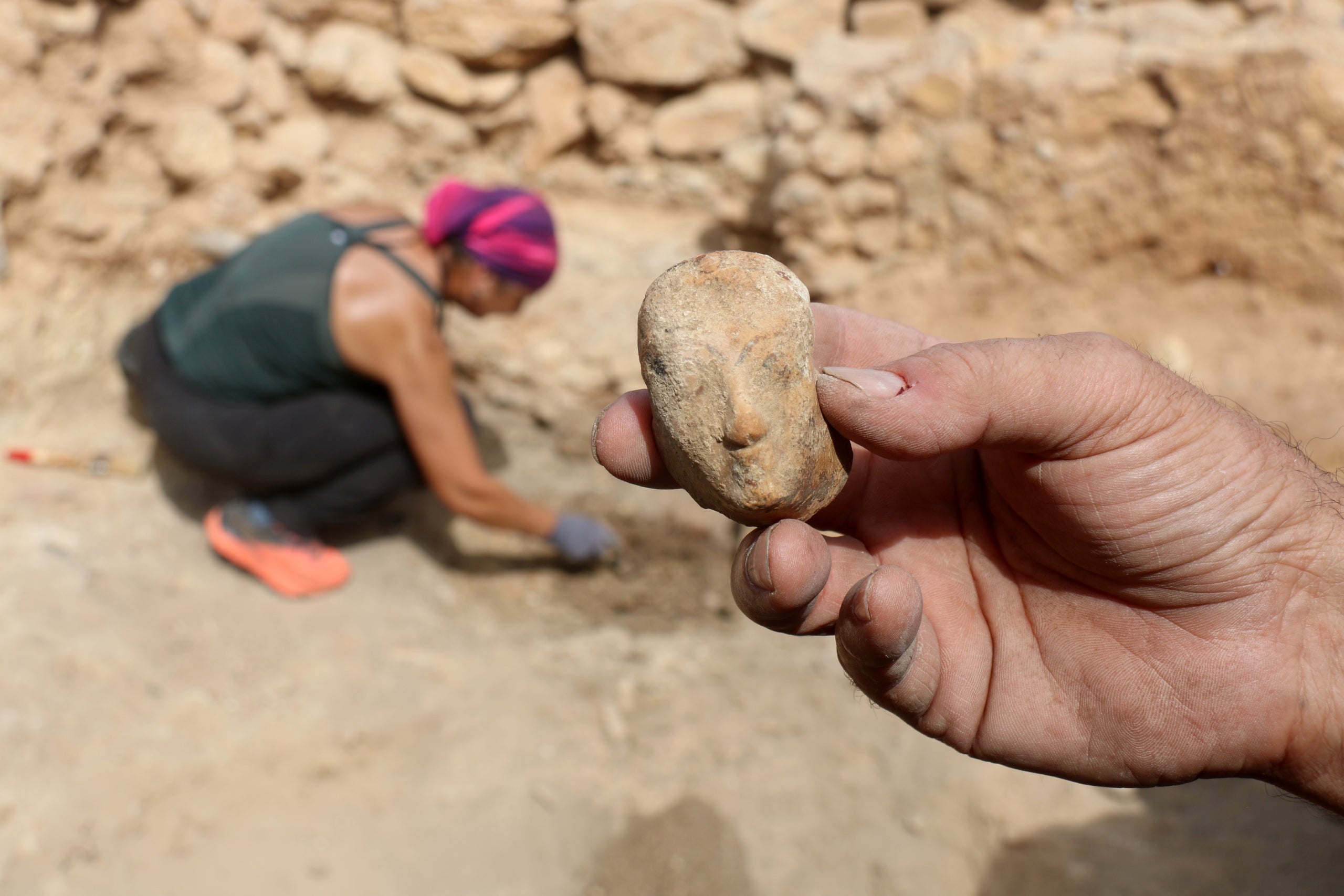 Detall de la mà de l'arqueòleg amb el cap femení que formava part de l'askos grec a la zona d'Empúries on s'ha localitzat | Xavier Pi (ACN)