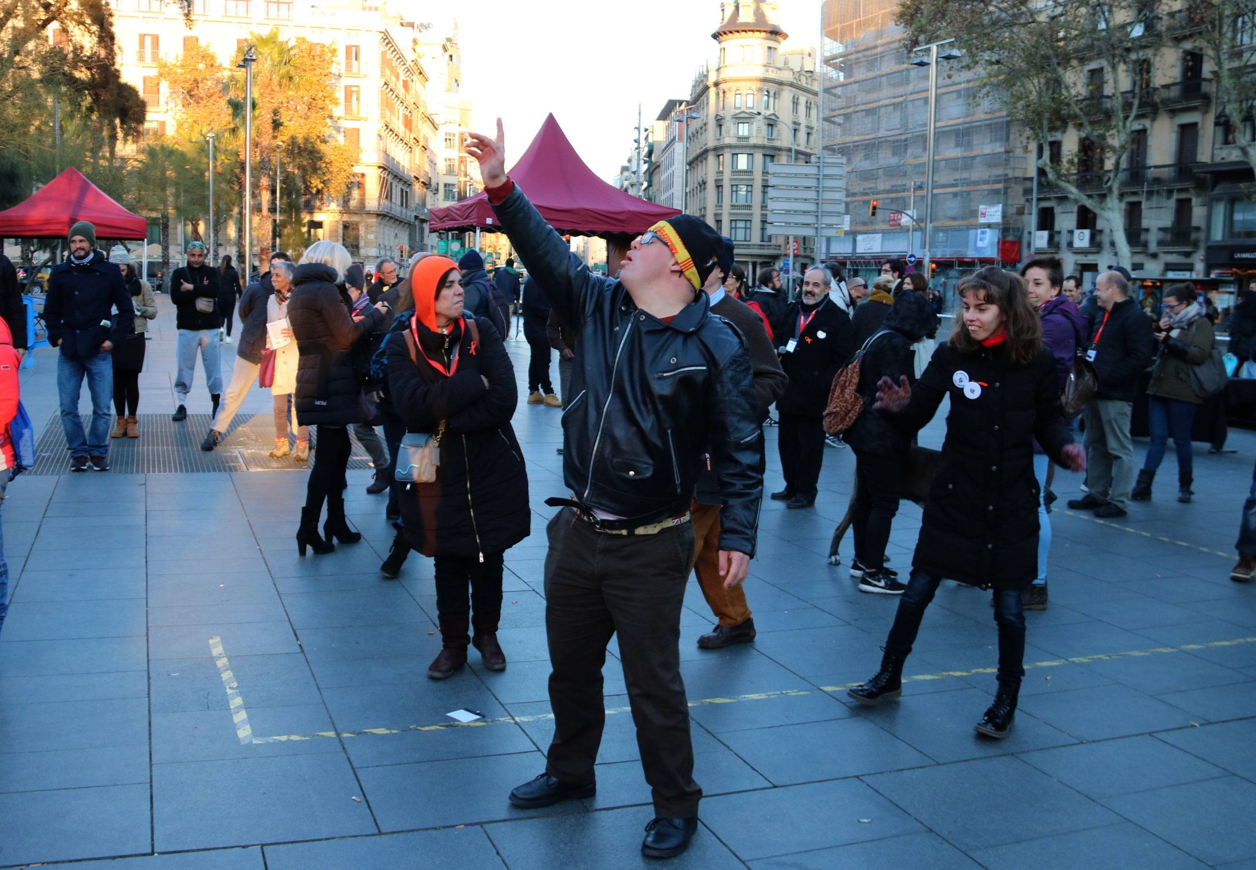 Un jove amb síndrome de Down balla durant una sessió de Discjòquei en la festa celebrada a la Plaça Universitat amb motiu del Dia Mundial de les persones amb Discapacitat Intel·lectual (03/12/2017). Pla General. (horitzontal) | Júlia Pérez (ACN)