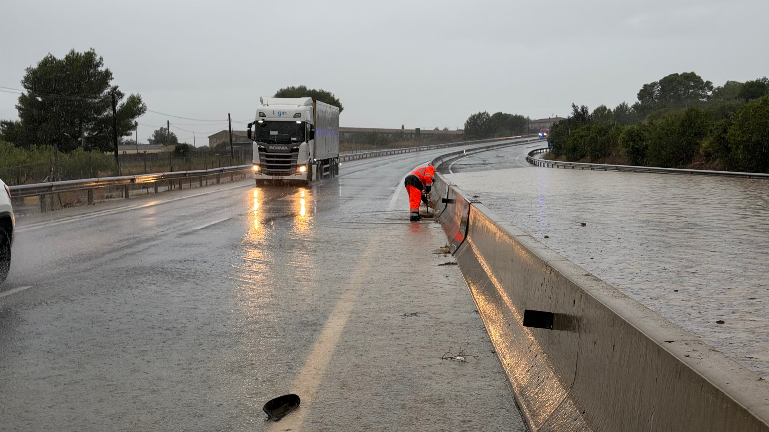 Un operari de carreteres intenta desembossar la inundació d’un carril de la C-42 entre  Tortosa i l’Aldea | ACN